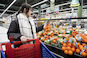 Vrouw in supermarkt bij een schap sinaasappels
